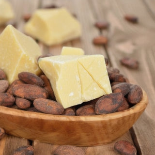 Kakaobohnen und Kakaobutterstücke in einer Holzschale