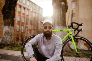 Mann mit Vollbart, Sonnenbrille und neongrünes Fahrrad im Hintergrund